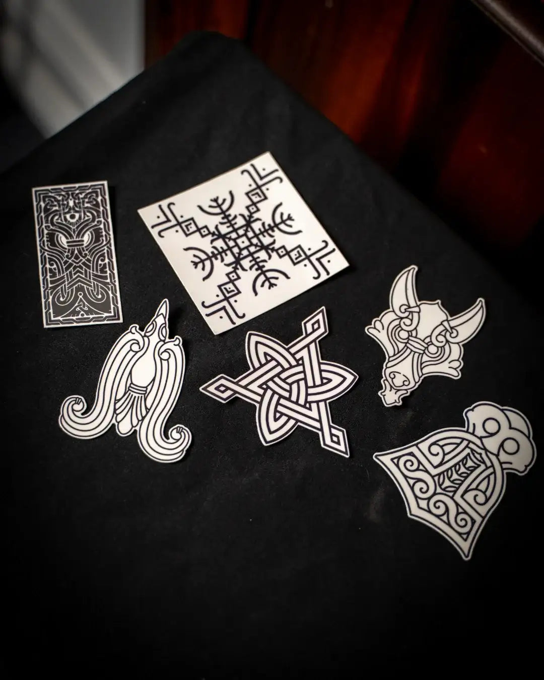 Viking tattoo designs and Norse symbols on black fabric, featuring runes, Valknut, and Odin-inspired art
