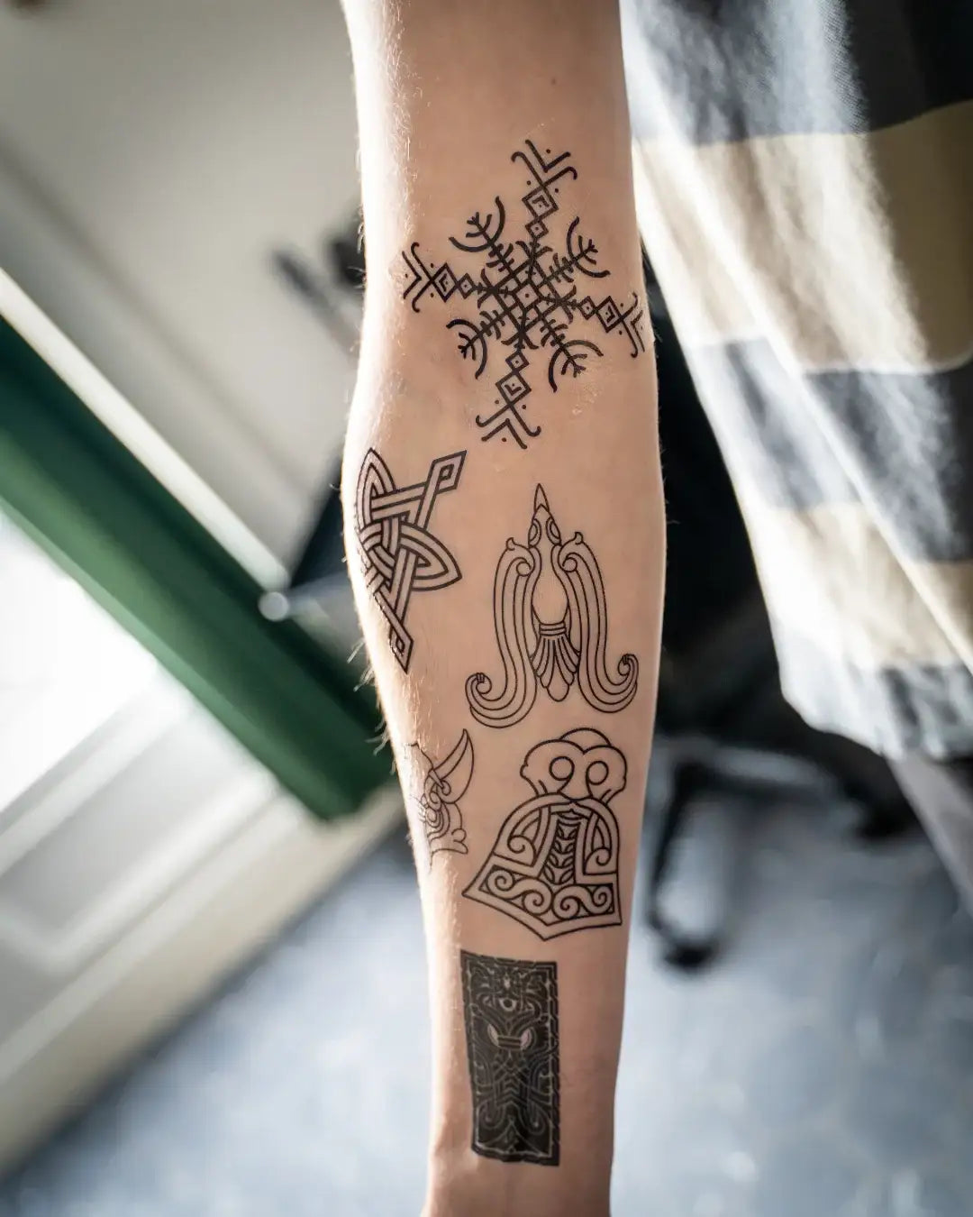 Viking tattoo designs on forearm: Norse runes, Celtic knots, and Odin-inspired art from authentic artifacts.