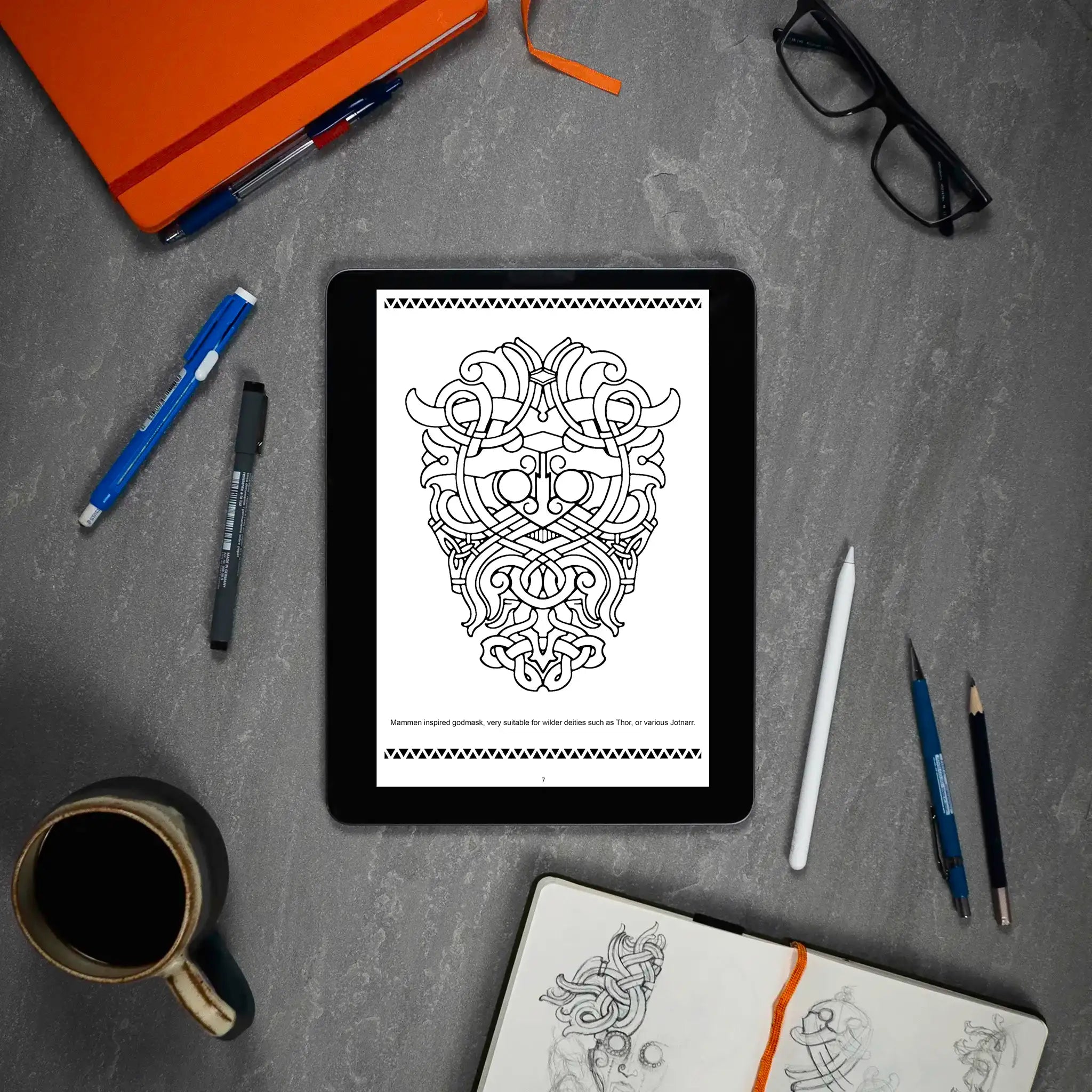 Mammen inspired Viking godmask tattoo design on tablet, ideal for Thor or Jotnar, surrounded by sketch tools and notebook.