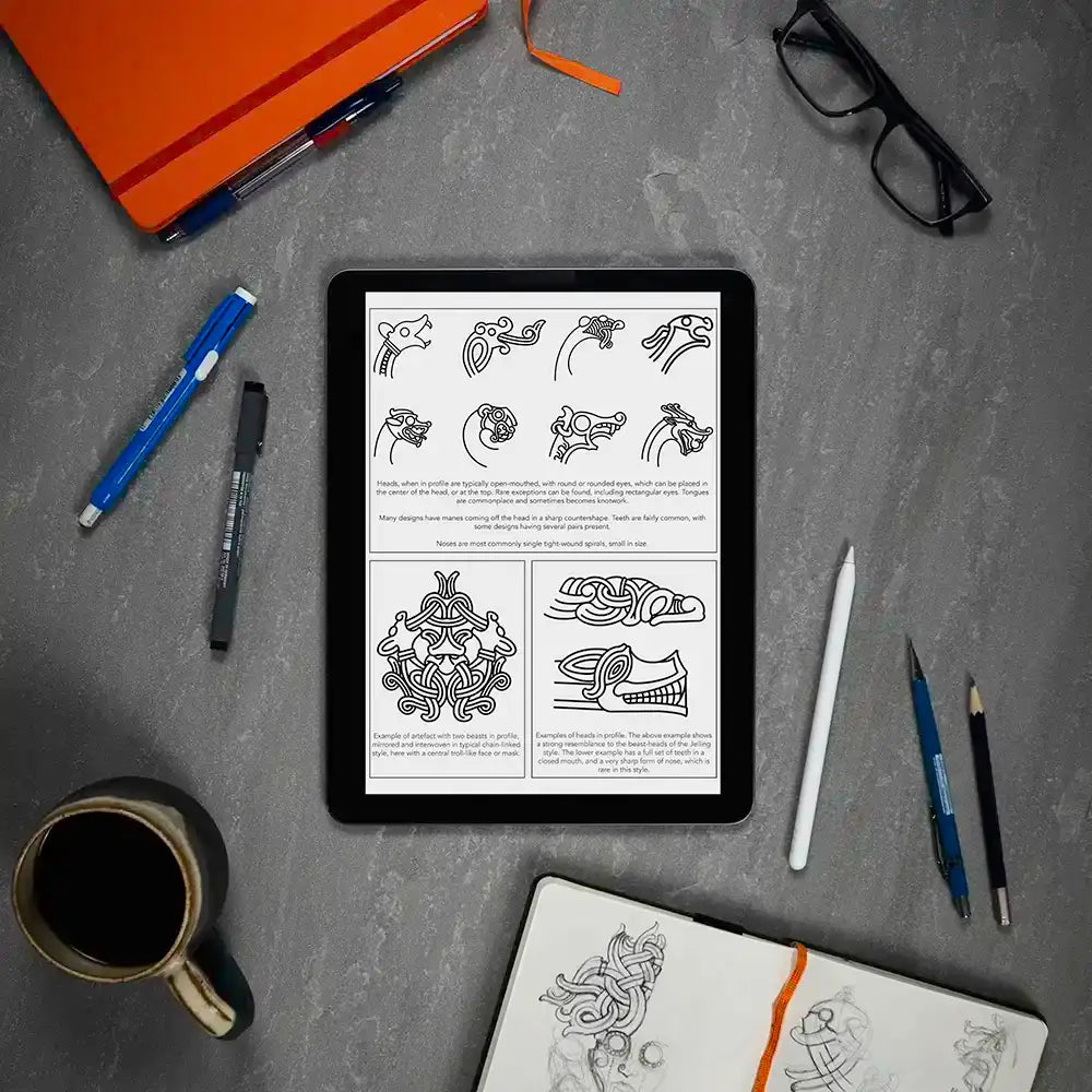 Viking tattoo design guide on tablet with Norse knotwork sketches, pens, and coffee — ideal for tattoo artists and enthusiasts.