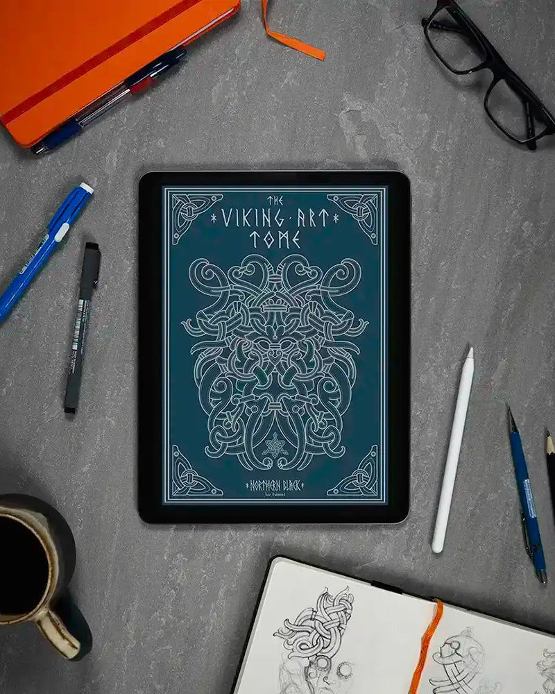Viking art tome digital display with Norse knotwork, surrounded by sketch tools and coffee on gray desk