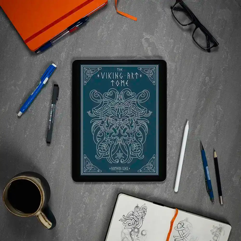 Viking art tome digital display with Norse knotwork, surrounded by sketch tools and coffee on gray desk