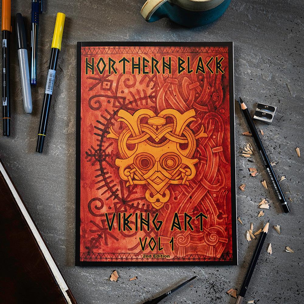 Northern Black Viking Art Vol 1 book with Norse knotwork design, surrounded by drawing tools on concrete