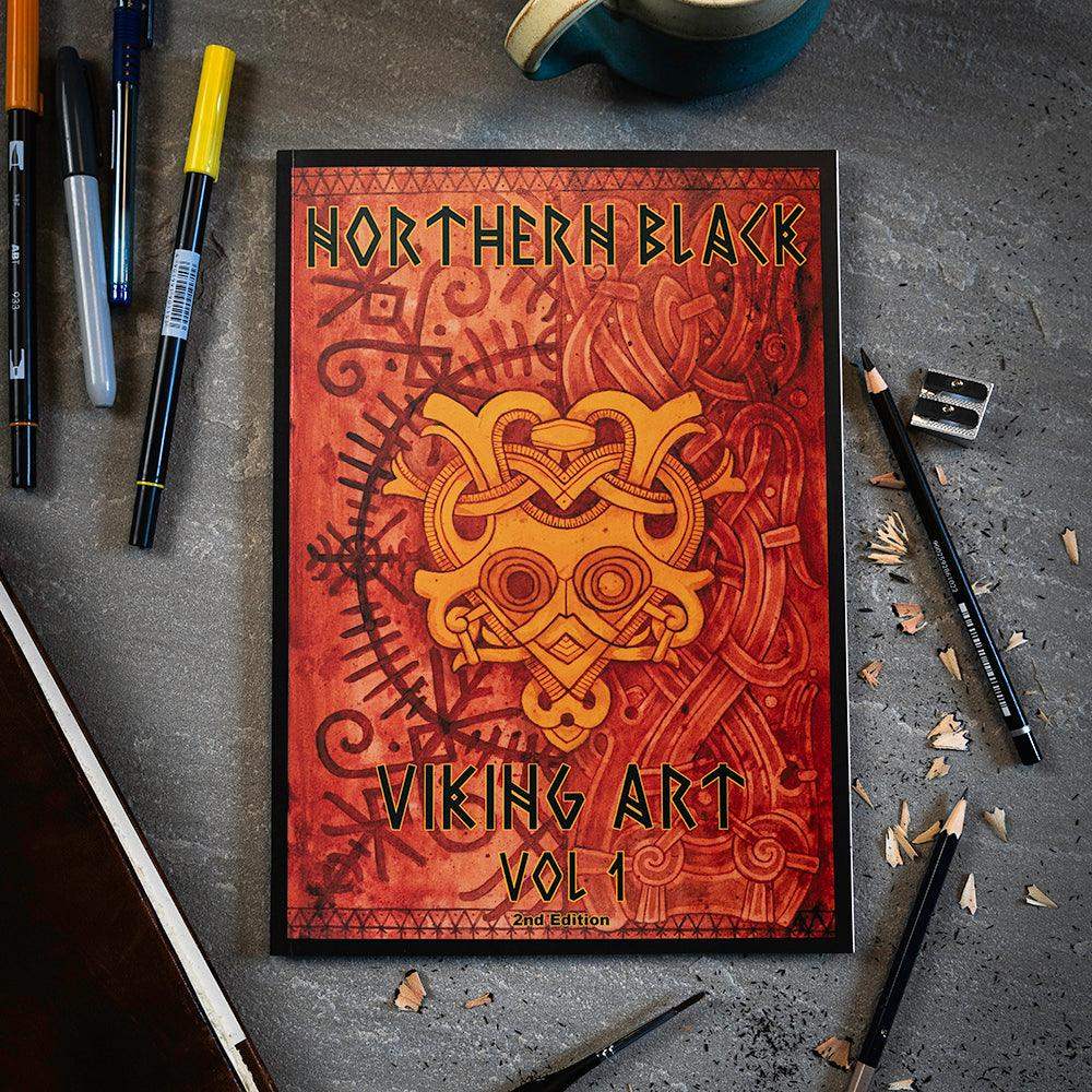 Northern Black Viking Art Vol 1 book with Norse knotwork design, surrounded by drawing tools on concrete