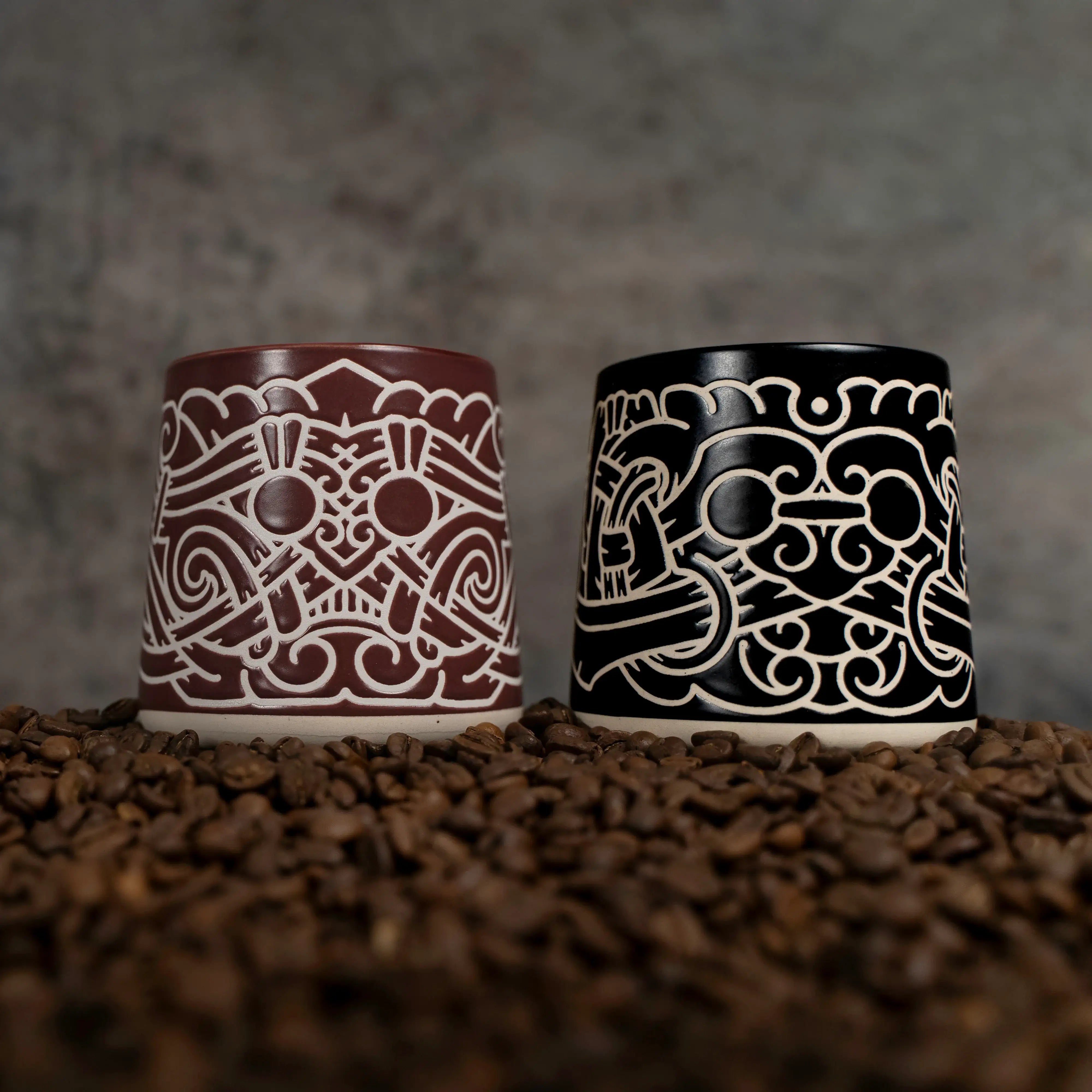 Two Viking-inspired ceramic mugs with intricate Norse knotwork designs, set on coffee beans.