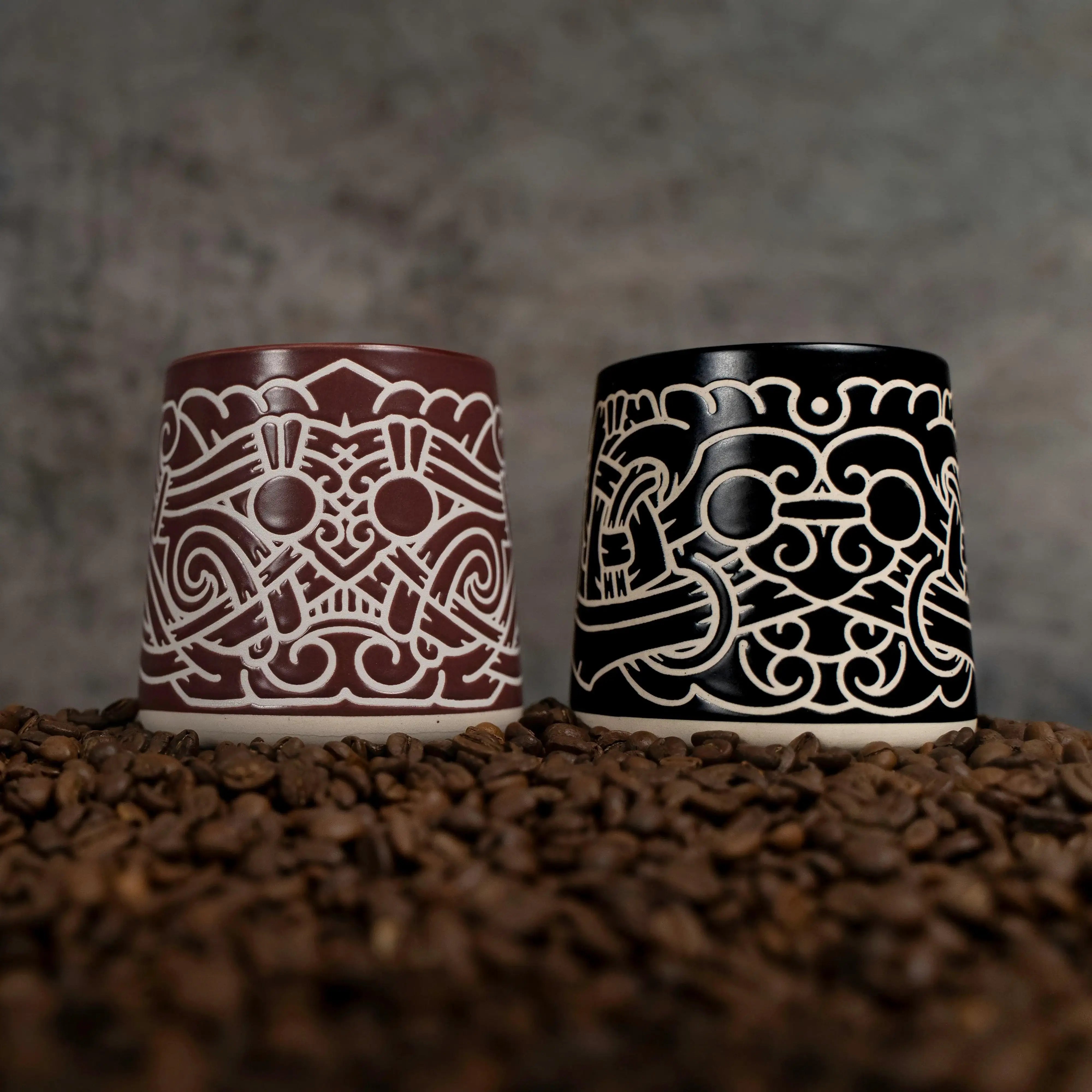Two Viking-inspired ceramic mugs with Norse knotwork designs, set on coffee beans.