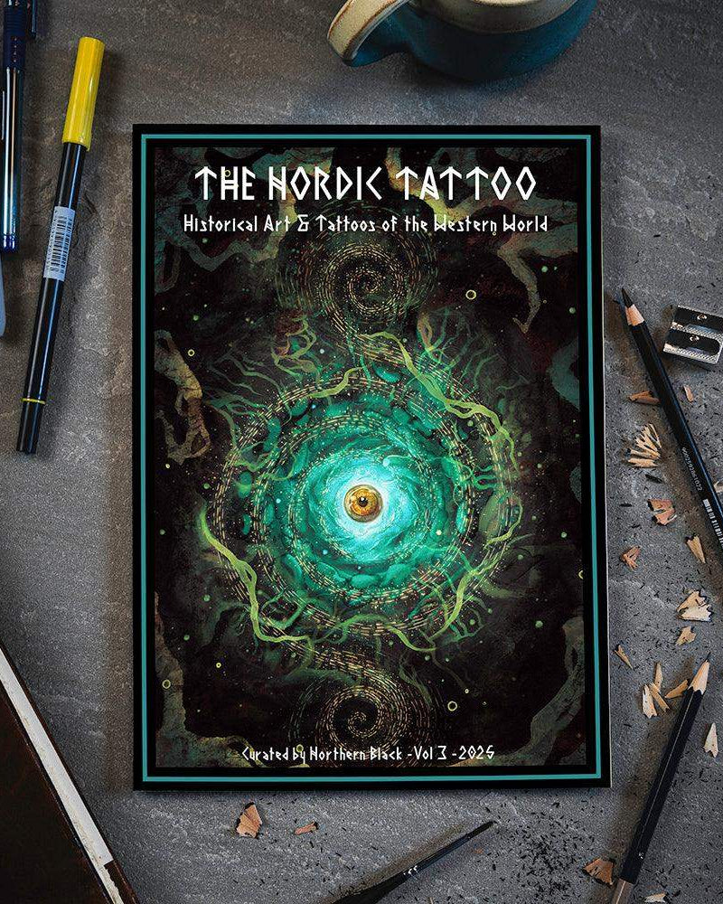 The Nordic Tattoo Vol 3 art book with swirling green eye design, surrounded by pens and pencils on gray desk