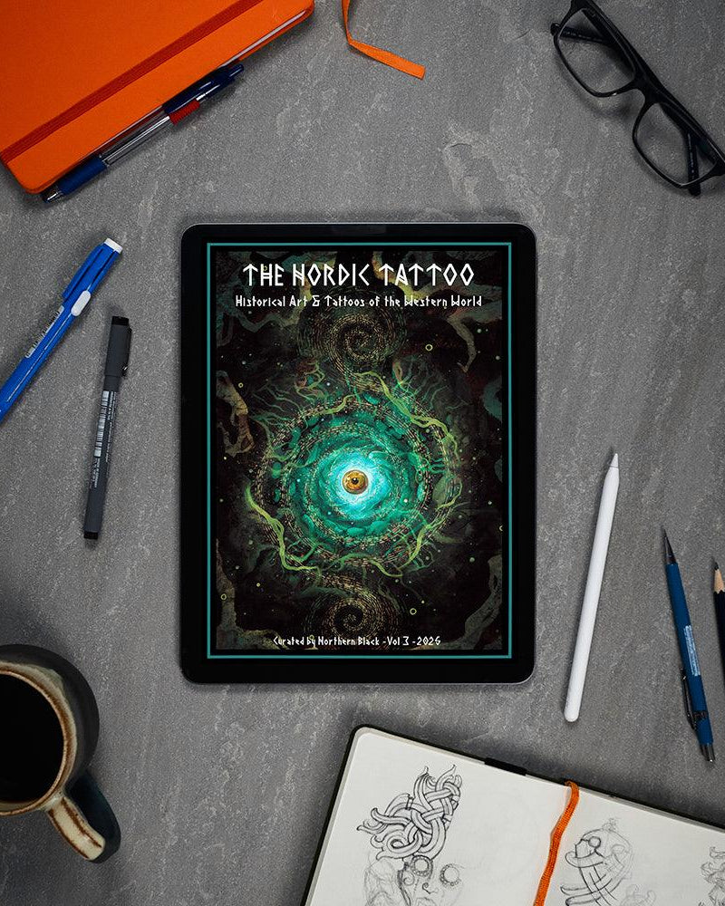 The Nordic Tattoo art book on tablet, surrounded by sketch tools and coffee, showcasing Viking-inspired designs