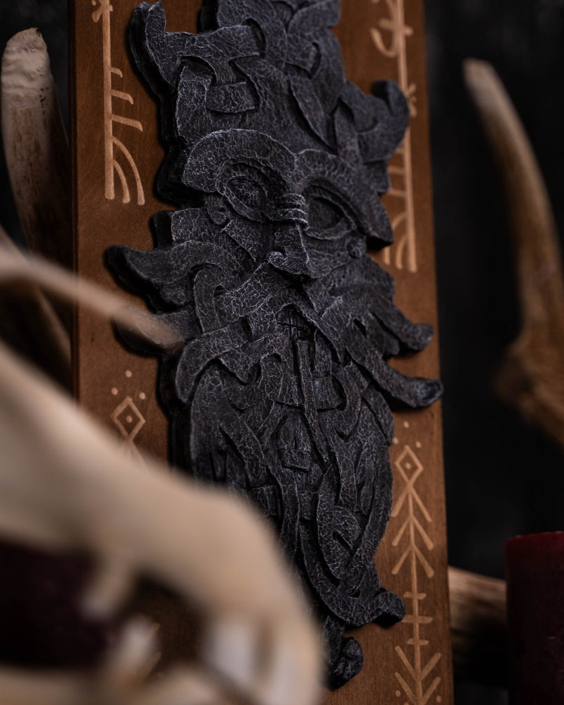 stonelike godmask of odin, put on a engraved wooden background with runes