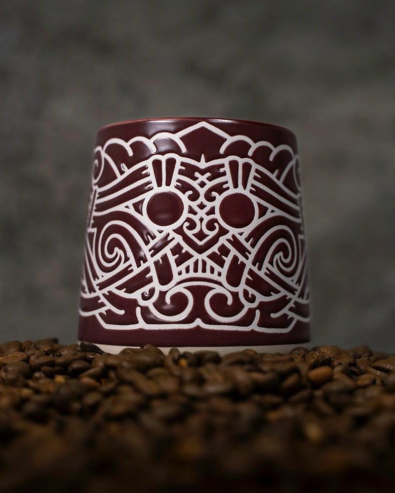 Viking-inspired ceramic mug with Norse knotwork design, set on coffee beans