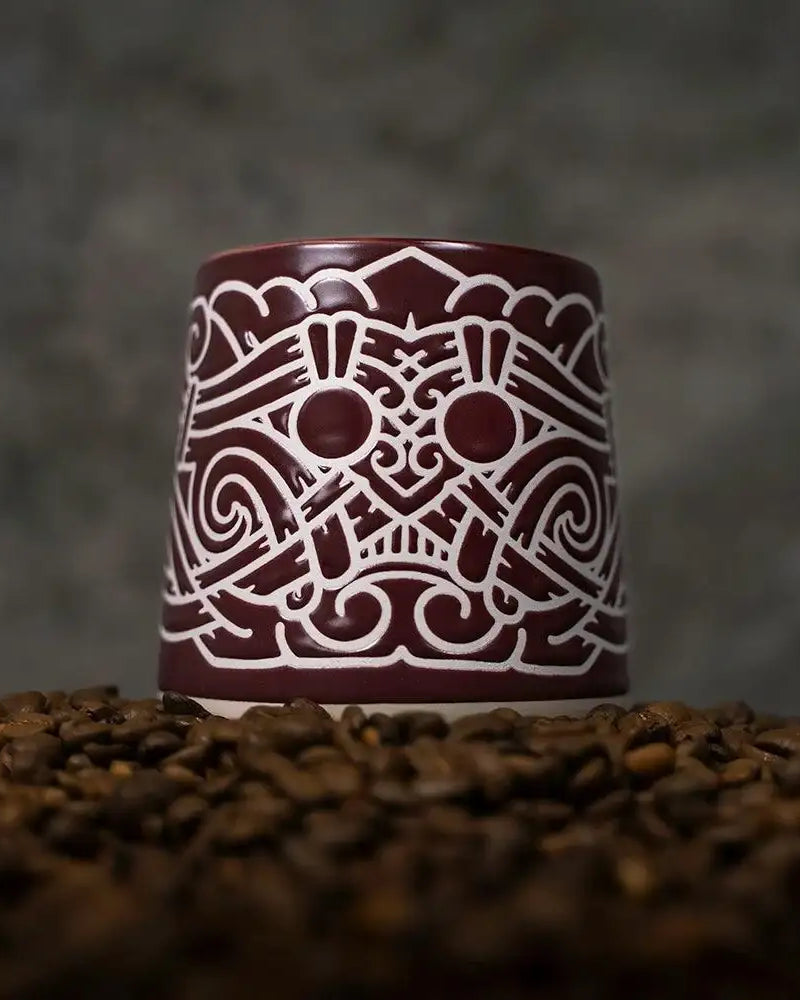 Viking-inspired ceramic mug with Norse knotwork design, set on coffee beans