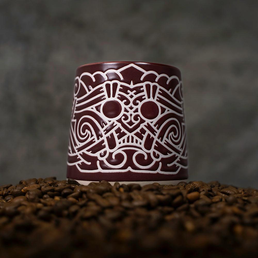 Viking-inspired ceramic mug with Norse knotwork design, set on coffee beans