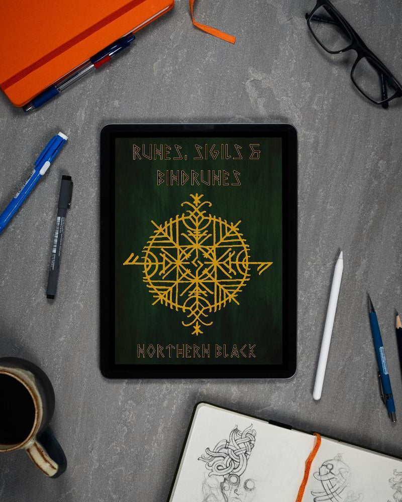 Viking rune art book on tablet with Norse designs, pens, sketchbook, and coffee — perfect for tattooists and Norse art lovers.