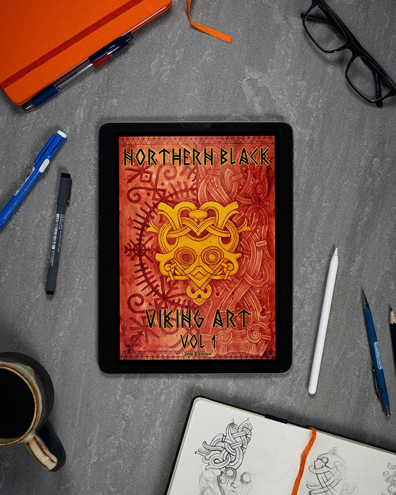 Northern Black Viking Art Vol 1 digital book on tablet, surrounded by sketch tools and coffee, showcasing Norse designs.