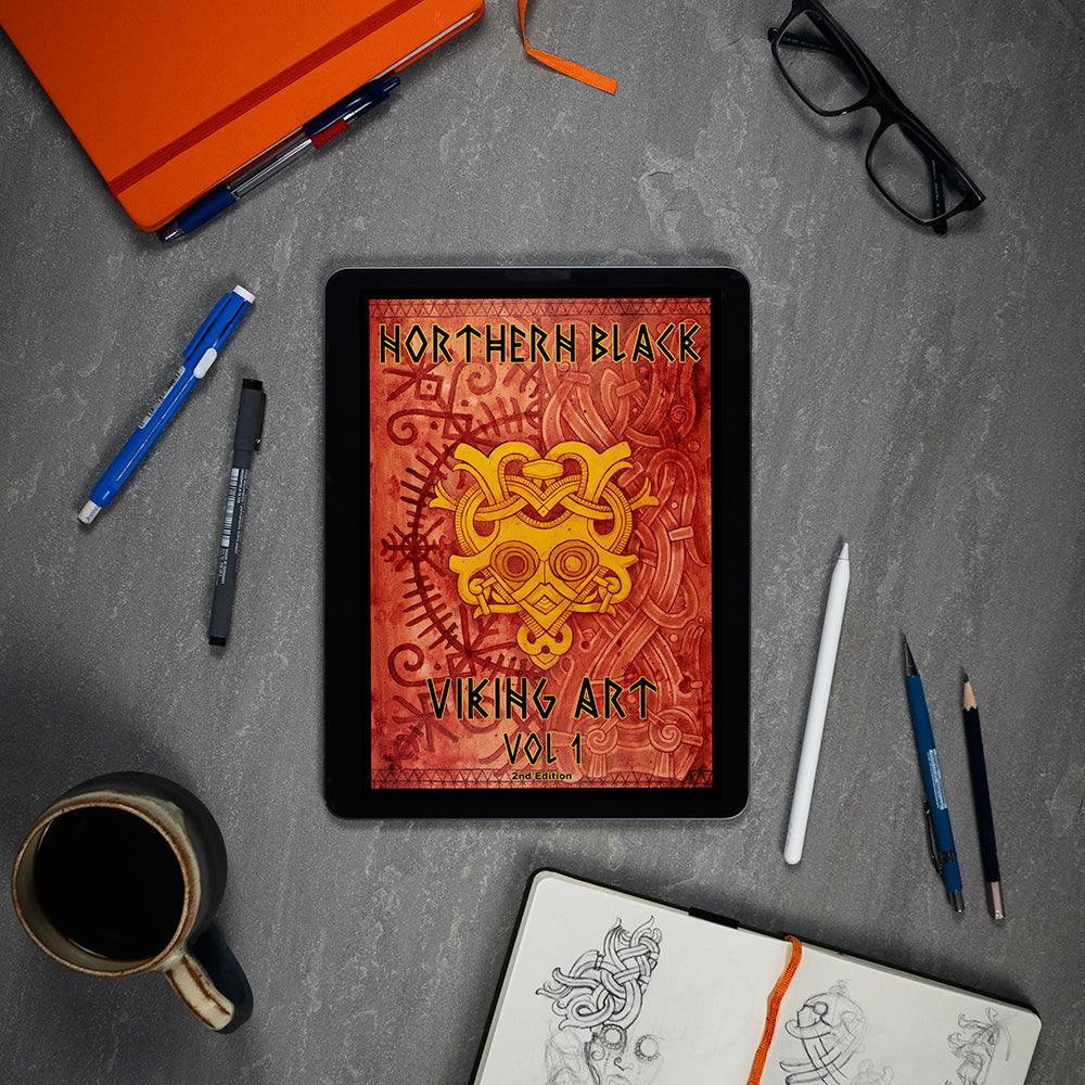 Northern Black Viking Art Vol 1 digital book on tablet, surrounded by sketch tools and coffee, showcasing Norse designs.