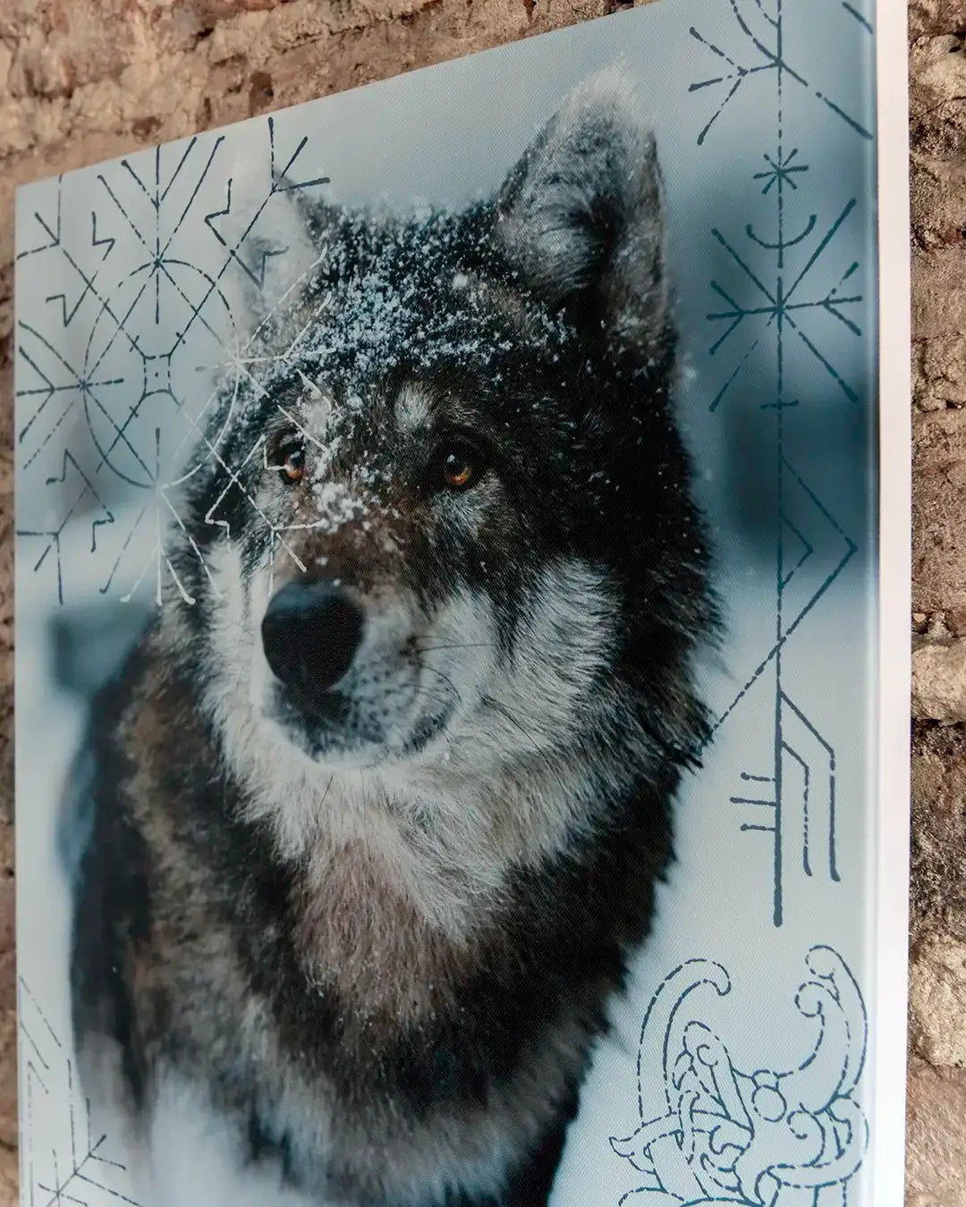 Snow-dusted wolf with Norse runes and Viking-inspired designs on artwork