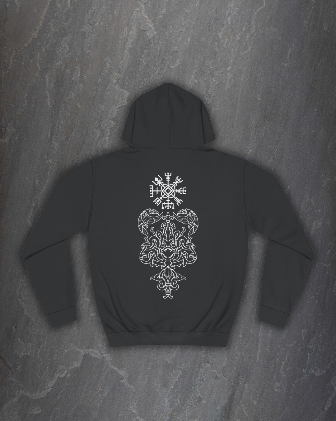 Back of a black Yggdrasil hoodie with a white Norse world tree and runic compass print on a dark slate background