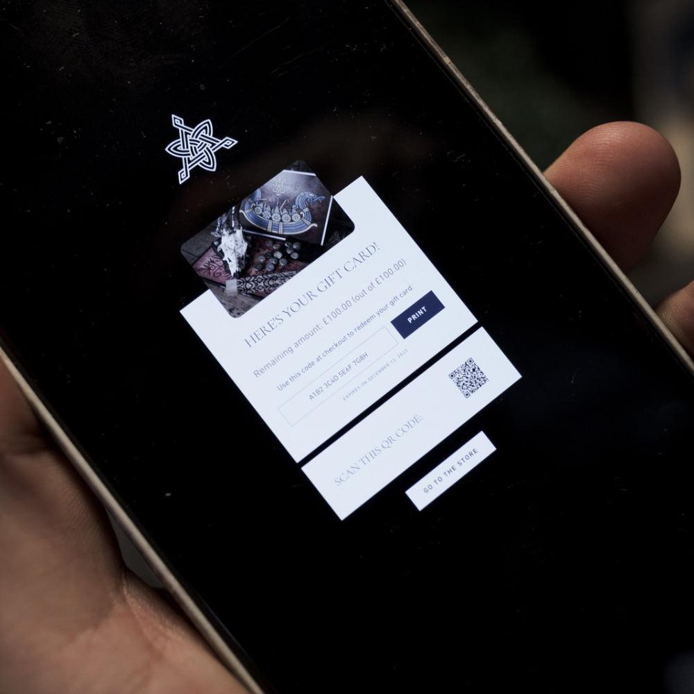 Digital gift card for Viking tattoo designs and Norse apparel displayed on smartphone with QR code