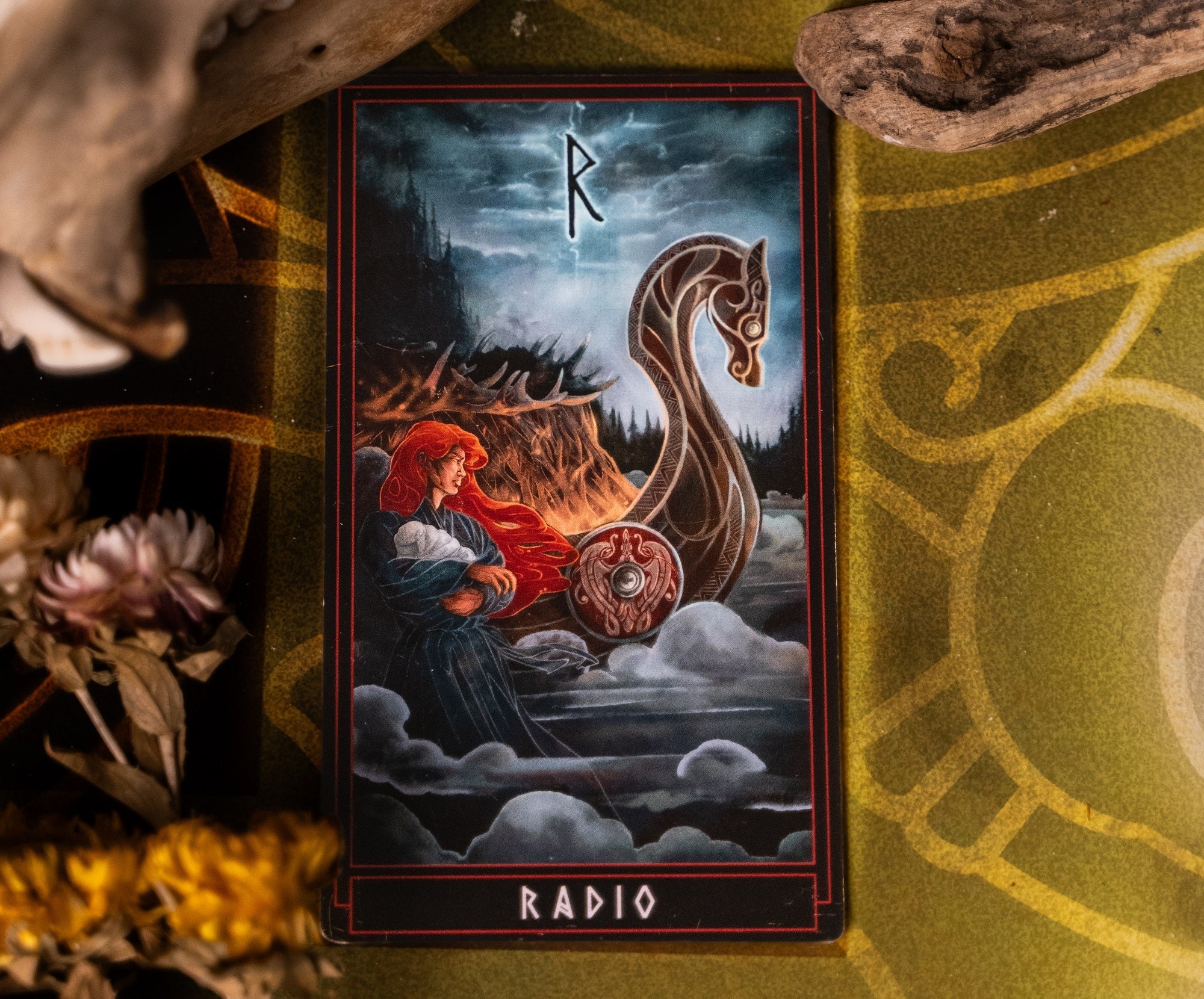 Illustrated tarot-style card featuring a red-haired woman standing beside a Viking longship