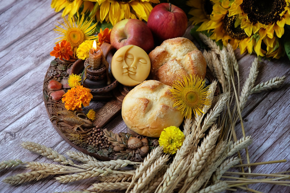 Lughnasadh offering table with fresh bread, sunflowers, apples, marigolds, and candles arranged with wheat stalks