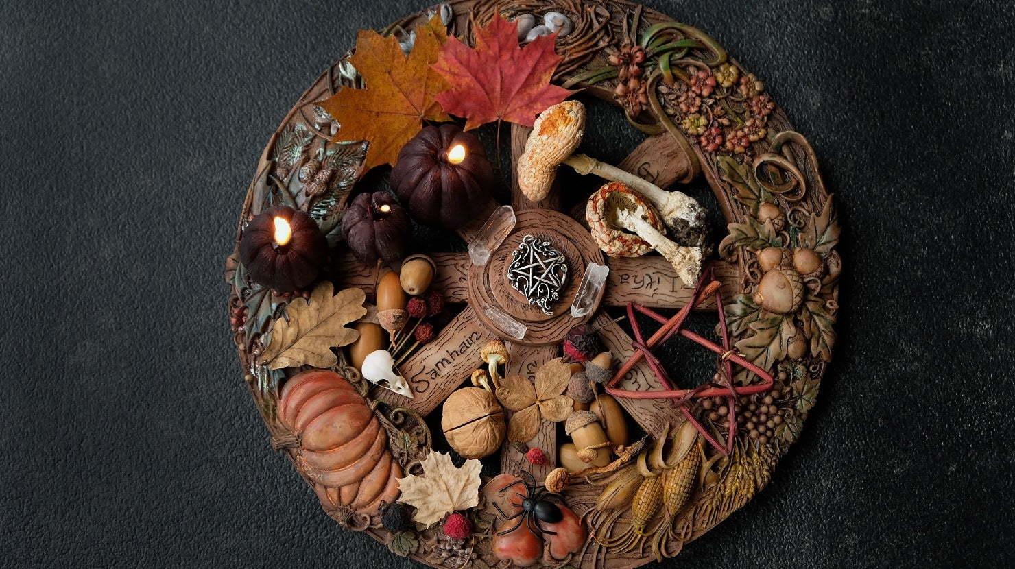 Samhain-themed wreath decorated with candles, autumn leaves, pumpkins, acorns, crystals, mushrooms, and a central pentacle charm on a dark textured background