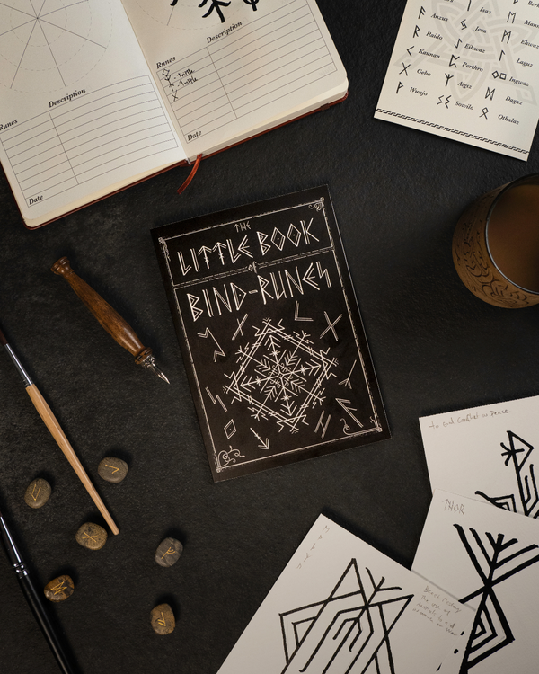 Little Book of Bind-Runes with Norse rune stones, sketchbook, and Viking-inspired tattoo designs on dark surface