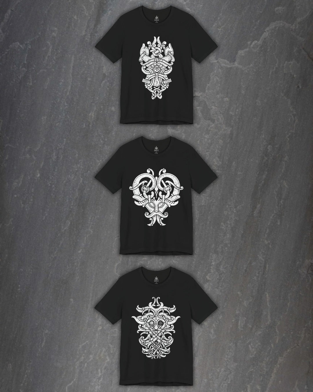 Three black short-sleeve t-shirts with intricate white godmask prints, arranged vertically on a dark gray textured stone background.
