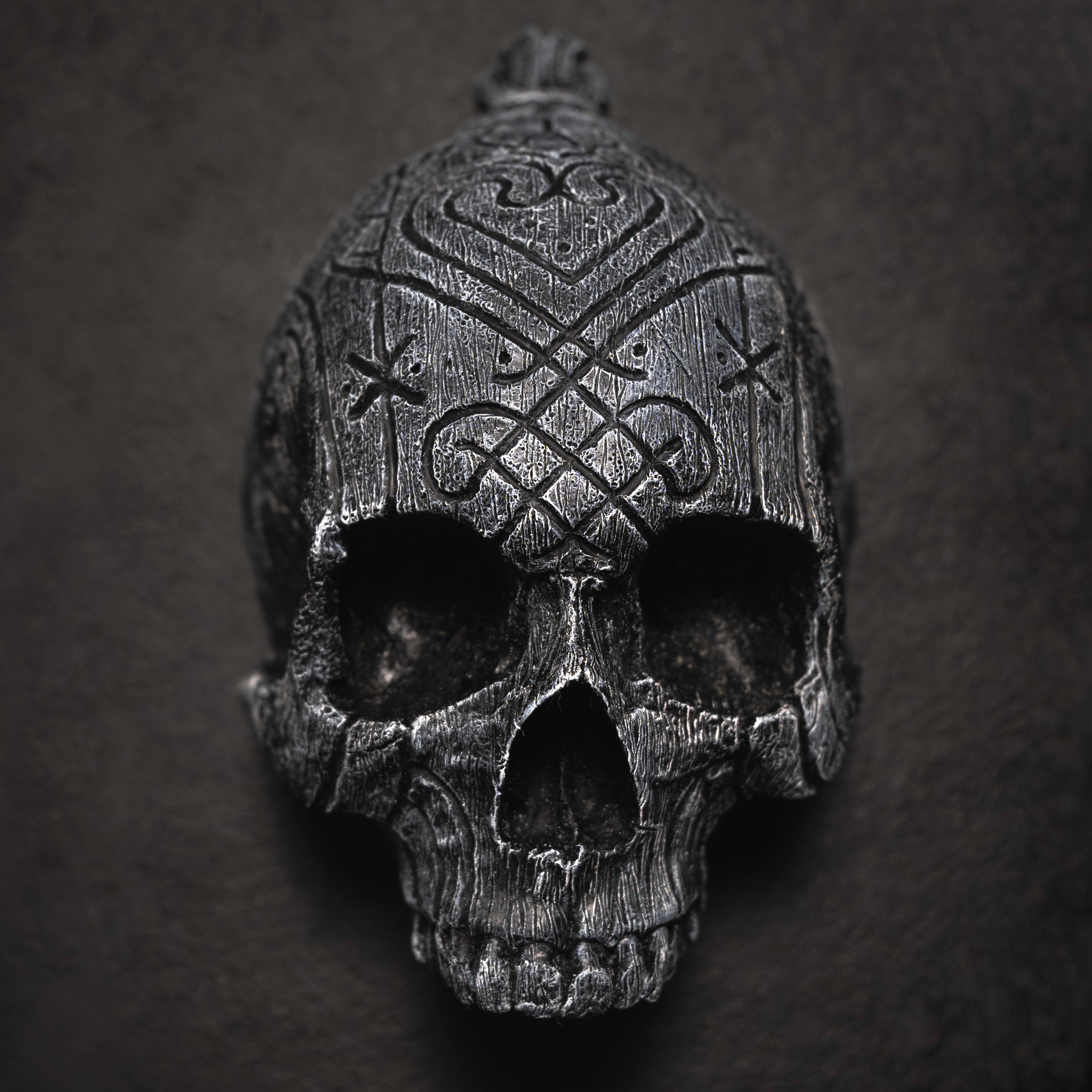 Depicting one of three skulls that are in a collection. They are resin human shaped skulls with runes on them, each representing one of the following: Love, Lust, Loss.