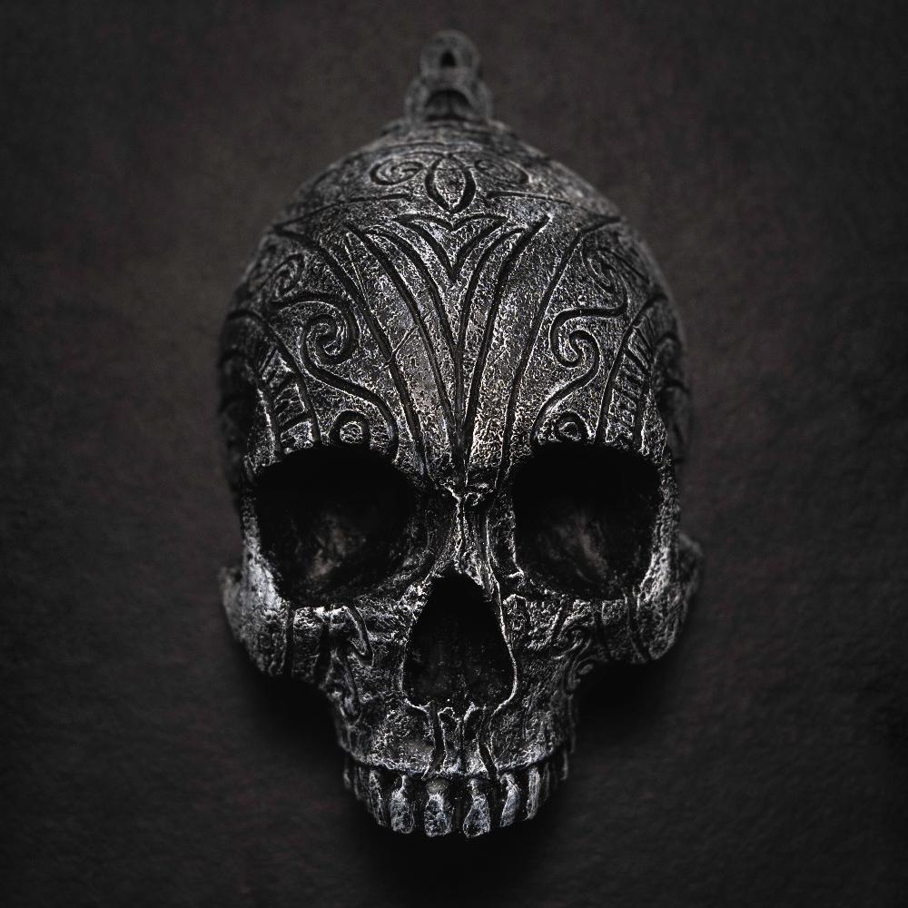 Depicting one of three skulls that are in a collection. They are resin human shaped skulls with runes on them, each representing one of the following: Love, Lust, Loss.