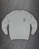 Front of a heather grey Odin Godmask sweatshirt with a small Northern Black logo on the chest on a dark slate background