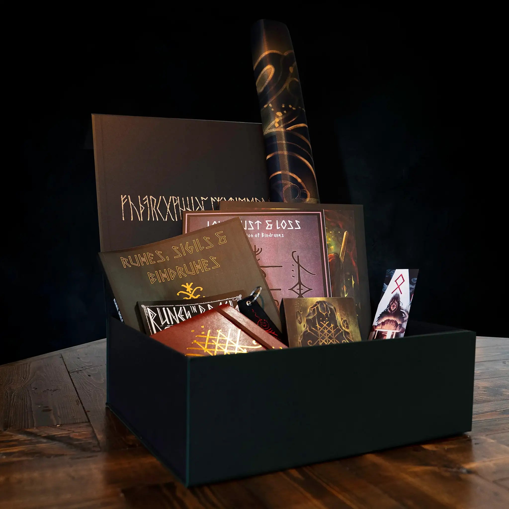 Norse-inspired gift box with runes, sigils, bindrunes books, art prints, and Viking-themed items on dark wood