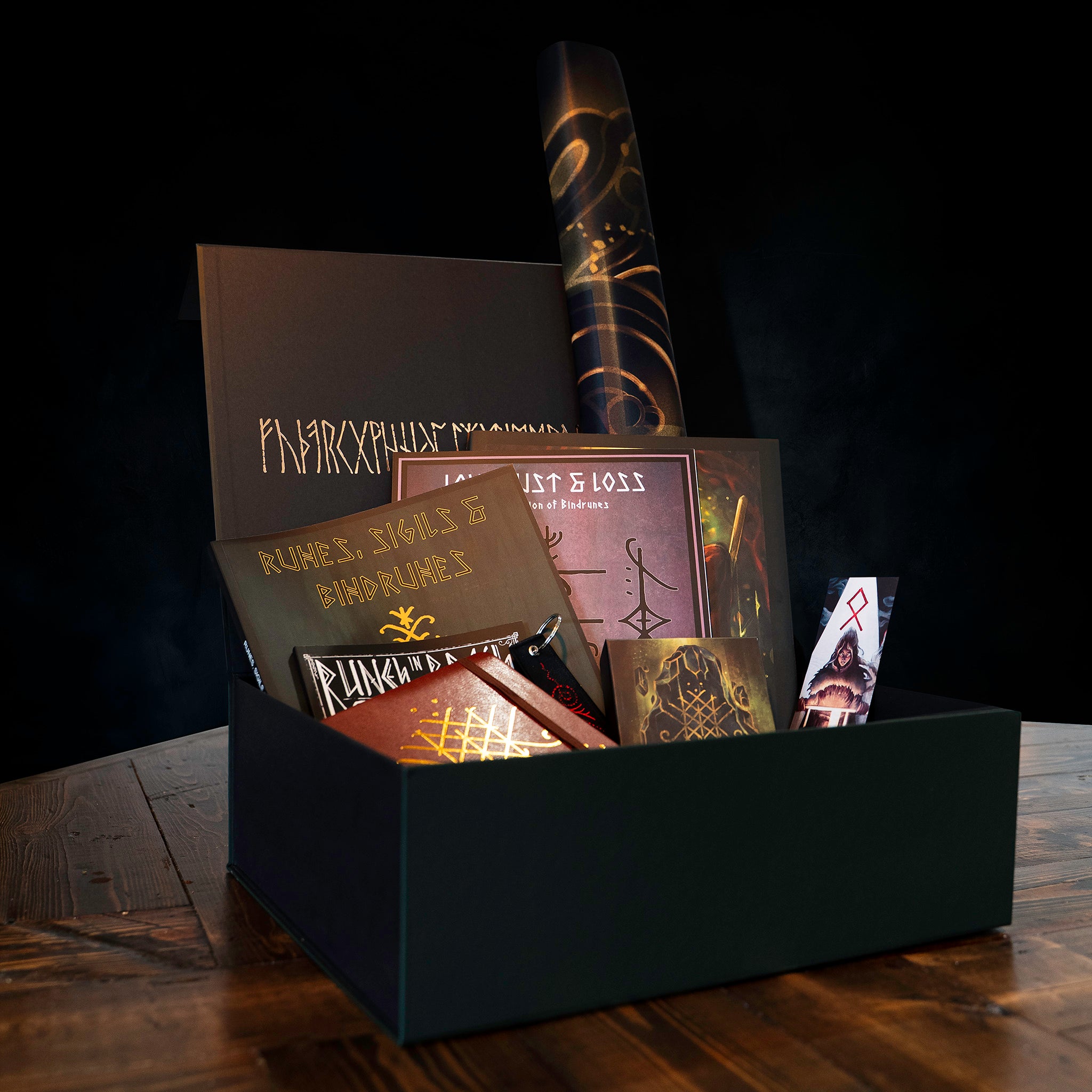 Norse-inspired gift box with runes, sigils, bindrunes books, art prints, and Viking-themed items on dark wood