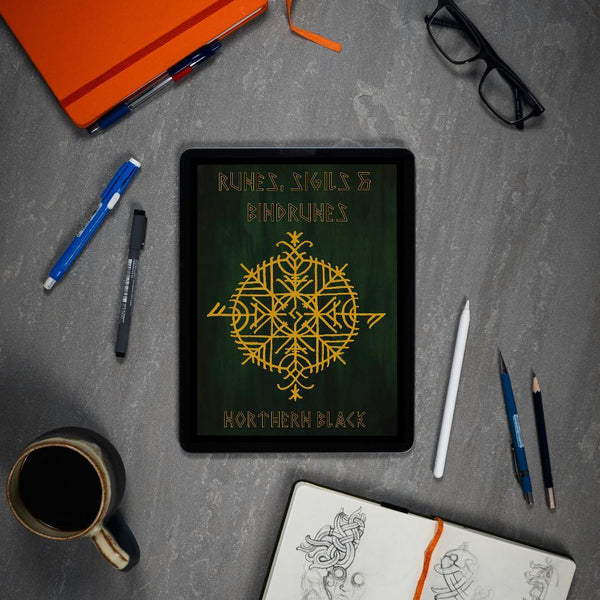 Viking rune art book on tablet with Norse designs, pens, sketchbook, and coffee — perfect for tattooists and Norse art lovers.