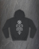 Back of a black Yggdrasil hoodie with a white Norse world tree and runic compass print on a dark slate background